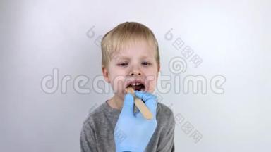 <strong>耳鼻喉</strong>科医生用木铲检查儿童的<strong>喉</strong>咙。 可能的诊断是咽炎，扁桃体发炎